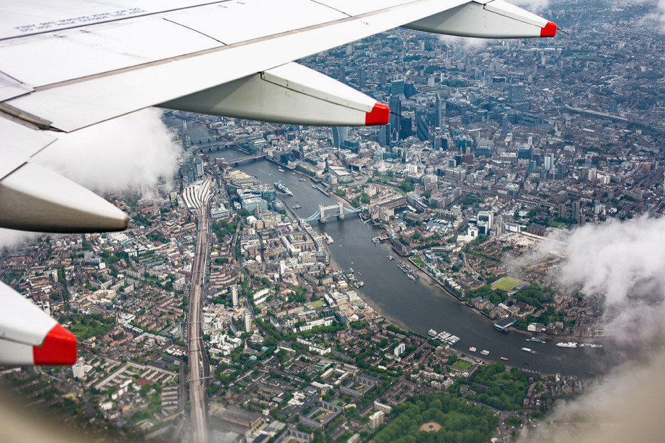 An airplane wing with the background of the city of London from the air.